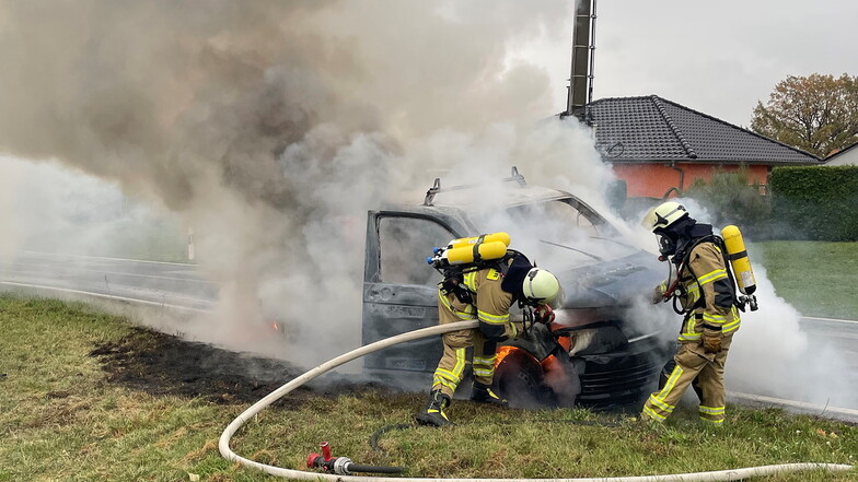 Feuerwehrleute löschen den brennenden Transporter.
