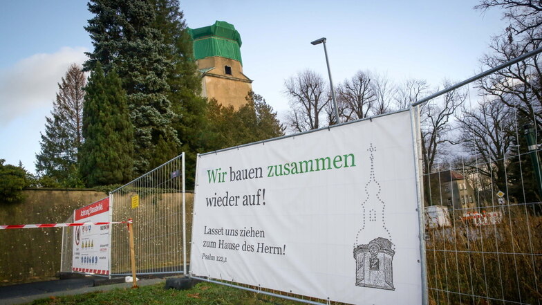 Am Absperrzaun vor der Kirche von Großröhrsdorf hängt ein großes Plakat, darauf steht: Wir bauen zusammen wieder auf!