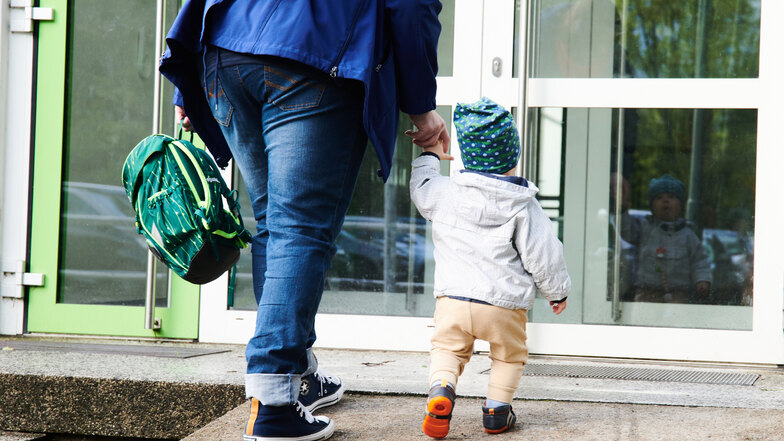 Ein Kind und seine Mutter gehen zum Eingang einer Kita. In Waldheim soll die Betreuung im Kindergarten und der Krippe teurer werden.