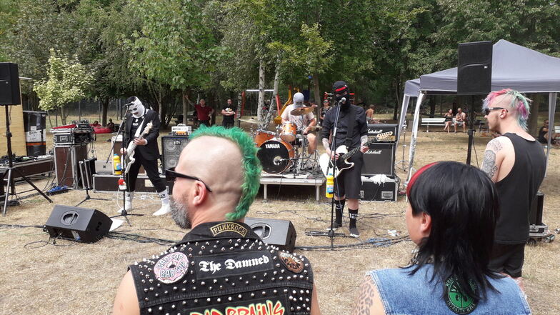 Die Band Soko Linx spielt im Waldbad und viele hören dem maskierten Trio zu.