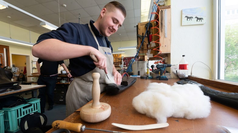 In der Sattlerei Büttner treffen traditionelles Handwerk und moderne Technik aufeinander. Richard Flechner (18 Jahre) füllt ein Sattelkissen mit Wolle.