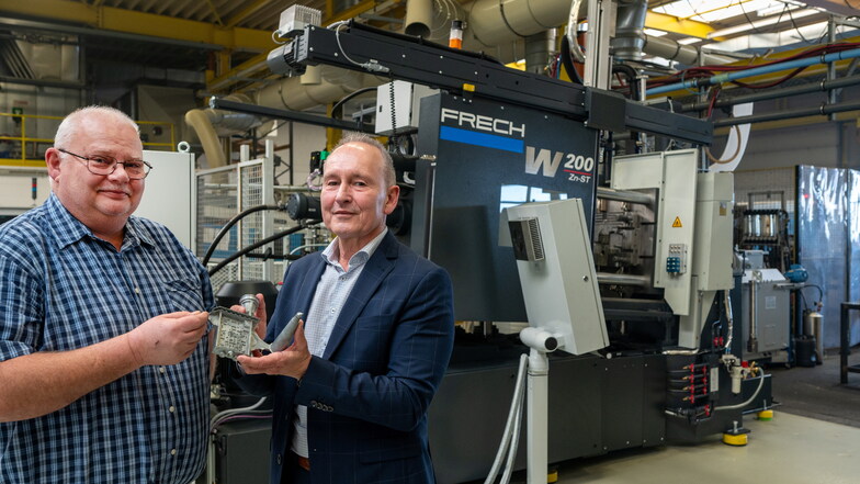 Produktionsleiter Mario Hahn (links) und Geschäftsführer Jörg Schöpp mit einem der ersten Teile, die im Probebetrieb der neuen Warmkammer-Druckgießmaschine hergestellt wurden.