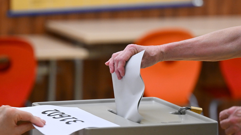 Eine Frau wirft einen Wahlzettel in einer Wahlurne.