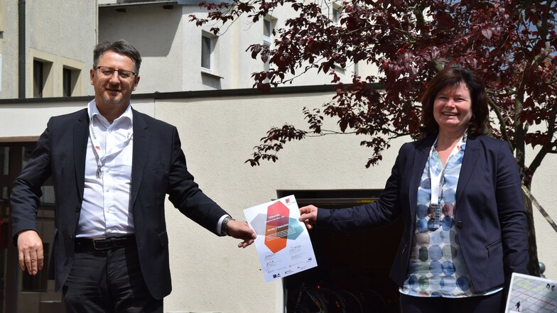 Oberbürgermeisterin Beate Hoffmann und Bürgermeister Ralf Brehmer mit der Urkunde in der Hand, sowie das Logo „Engagierte Stadt“