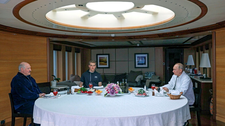 Alexander Lukaschenko (l.) frühstückt gemeinsam mit seinem Sohn Nikolai und Wladimir Putin auf einem Boot.