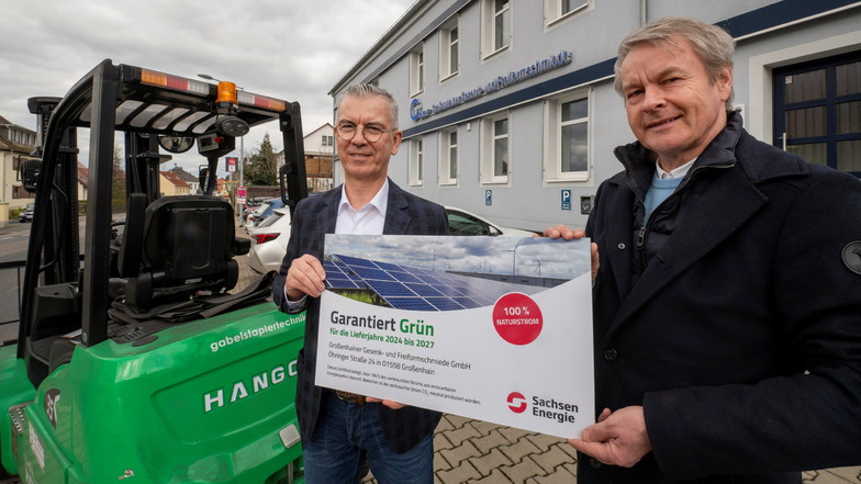 Der Geschäftsführer der Großenhainer Gesenk- und Freiformschmiede, Wolfgang Pradella (l.), bekommt von Sachsen-Energie-Kundenberater Thomas Horn das Zertifikat für grüne Energie. Im Hintergrund der grüne Stapler.