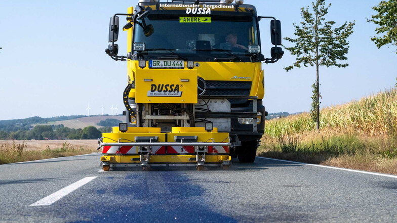 Ein Spezialfahrzeug reinigt die Straße in Spitzkunnersdorf von blauer Farbe.