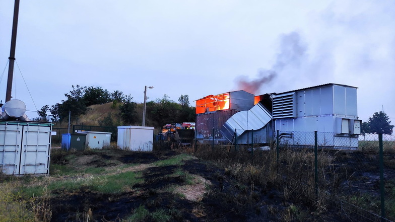 Die noch brennende Trocknungsanlage der Biogasanlage in Oberlommatzsch. Die umliegenden Wiesen sind bereits vom Brand geschwärzt.
