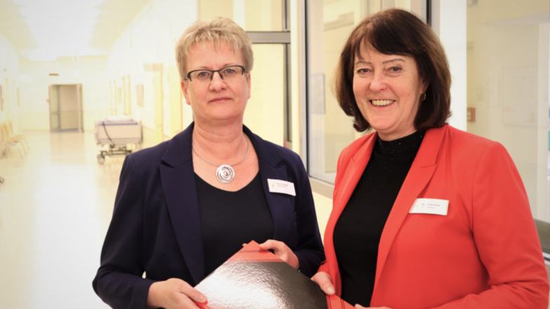 Marion Bandow (rechts) und Annett Berger überreichen sich symbolisch das „Buch der Pflegeweisheiten“ mit Notizen, Tipps und Hinweisen für eine erfolgreiche und reibungslose Übergabe der Funktion.