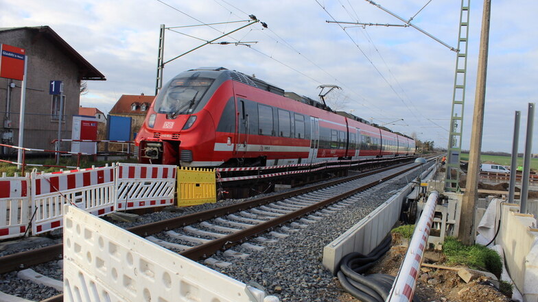 Ein Personenzug fährt am Glaubitzer Bahnhof an zahlreichen rot-weißen Absperrungen vorbei, die die Bauleute aufgestellt haben. Aber so richtig viel geschieht hier momentan nicht.