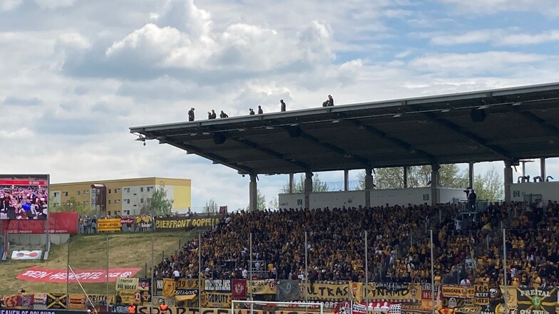 Auf dem Stadiondach stehen Dresdner Fans, die eine Choreografie vorbereiten.