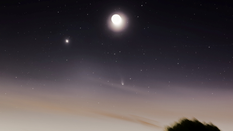 Der Planet Jupiter, der Mond und der sehr tief stehende Komet 12P/Pons-Brooks stehen etwa eine Stunde nach Sonnenuntergang am Abendhimmel am Horizont.