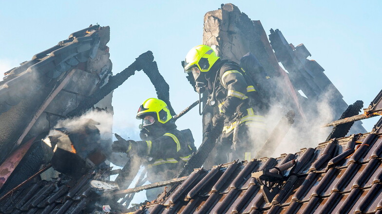 Feuerwehrleute entfernen die Ziegel auf der vom Feuer betroffenen Dachhälfte. Nach einer ersten Einschätzung von Feuerwehrleuten dürfte die Haushälfte vorerst unbewohnbar sein.
