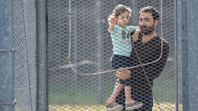 Eisenhüttenstadt: Ein Vater aus dem Irak hält seine Tochter in den Armen und steht an einem Zaun in der Zentralen Erstaufnahmeeinrichtung für Asylbewerber (ZABH) des Landes Brandenburg.
