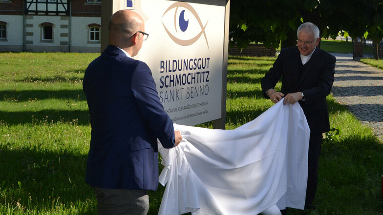 Vor dem neuen Bildungsgut in Schmochtitz enthüllen Rektor Sebastian Kieslich (l.) und Bischof Heinrich Timmerevers die Tafel mit dem Namen.
