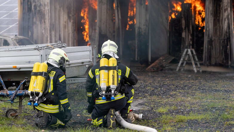 Zwei Feuerwehrmänner mit Atemschutz rücken im Priestewitzer Solarpark, Ortsteil Medessen, dem Feuer des brennenden Energiespeichers zu Leibe.