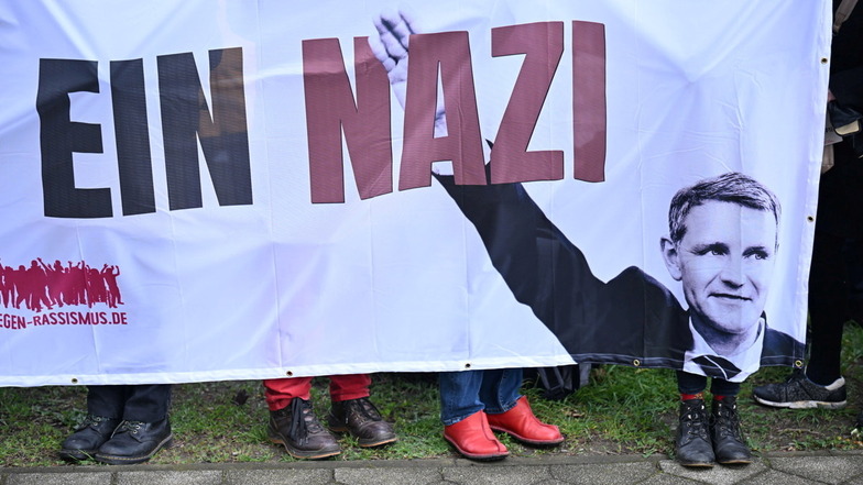 Demonstranten in Halle stehen mit einem Plakat mit der Aufschrift "Björn Höcke ist ein Nazi" vor dem Justizzentrum.
