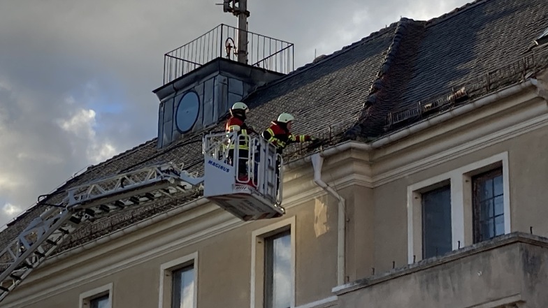 Von der Drehleiter aus entfernen Feuerwehr-Kameraden die gefährlichen Dachschindeln.