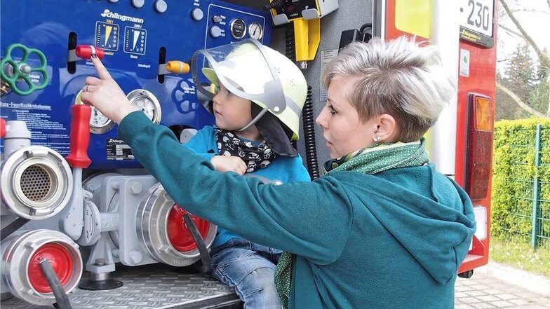 Der kleine Karl, wie man sieht schon ein begeisterter Feuerwehrmann, und seine Mutti Melanie Marx sehen sich beim Feuerwehrgeburtstag eine Feuerwehrkreiselpumpe an.