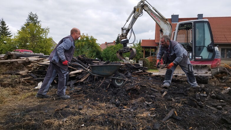 André Kambach (links) und Ingo Renner räumen die Reste des abgebrannten Schuppens in Ebersdorf weg.