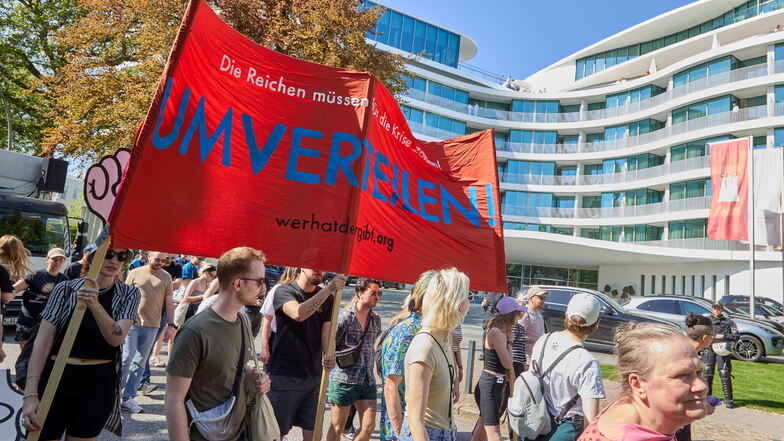 Teilnehmer einer Demonstration ziehen mit einem Transparent mit der Aufschrift: "Umverteilen" durch Hamburg.