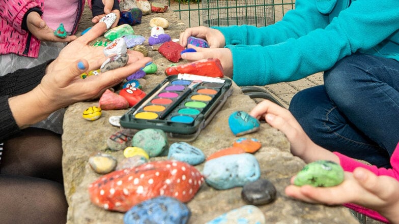 Diese bemalten Steine können unter den Kindern getauscht werden und werden vor der Kita auf einer Steinmauer ausgestellt.