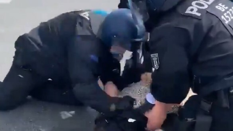 Polizisten drücken eine Frau am Rande einer Demo in Berlin auf den Boden.