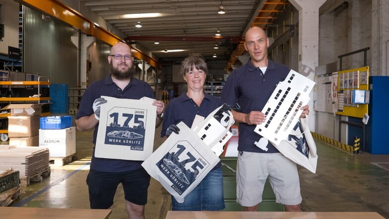 Vincent Göldner, Sandra Schneider und Ralf Mikonya (von links) verteilen Jubiläumsbeutel und Rohlinge, mit denen an verschiedenen Stationen im Werk ein Waggon gebaut werden kann.