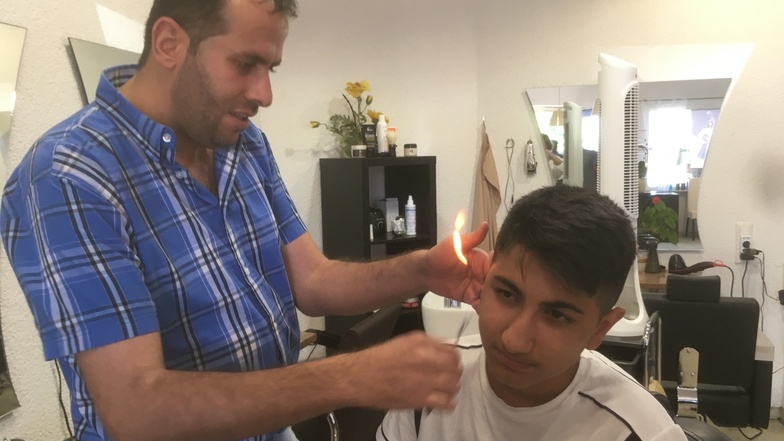 Mit einem Stück brennender Watte flämmt Friseur Waseem Ohr-Haare ab.