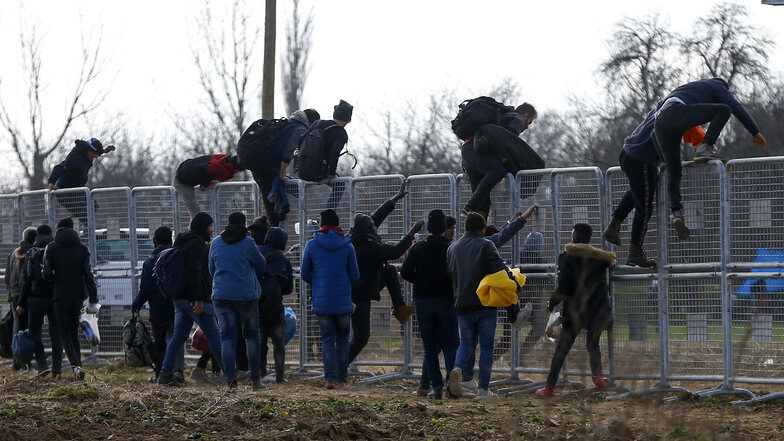 Flüchtlinge klettern über einen von den türkischen Behörden in der Nähe der Grenze errichteten Zaun.