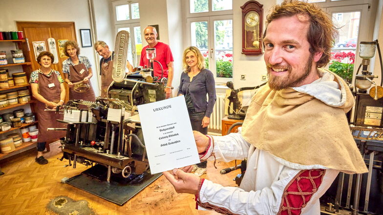 Gabor Schuster mit einer frisch gedruckten Buchpaten-Urkunde. Im Hintergrund an der Presse stehen die Besitzer vom Kuckuckstein, Susanne und Jens Höhnel.