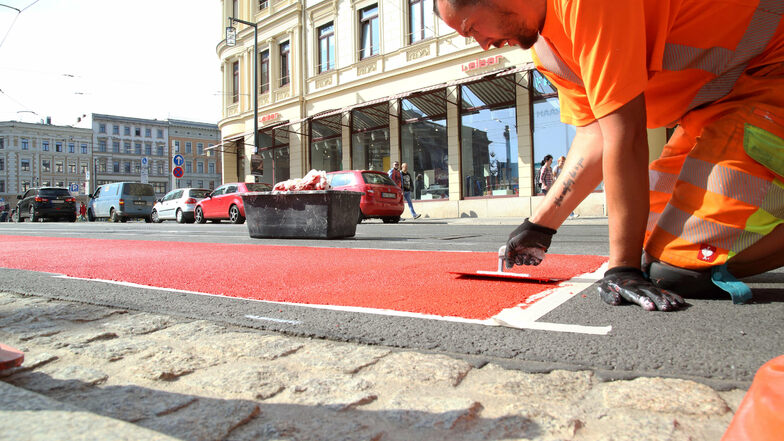 Alex Rutta spachtelt die rote Farbe auf den Asphalt.
Die Firma Verkehrstechnik Seifert markiert am Postplatz in Görlitz die Fahrbahn.
