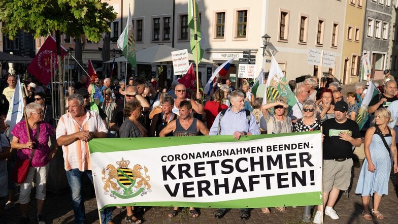 Teilnehmer einer Kundgebung der rechtsextremen Kleinstpartei Freie Sachsen stehen anlässlich einer CDU-Wahlkampfveranstaltung auf dem Marktplatz und tragen ein Transparent mit der Aufschrift «Kretschmer verhaften»