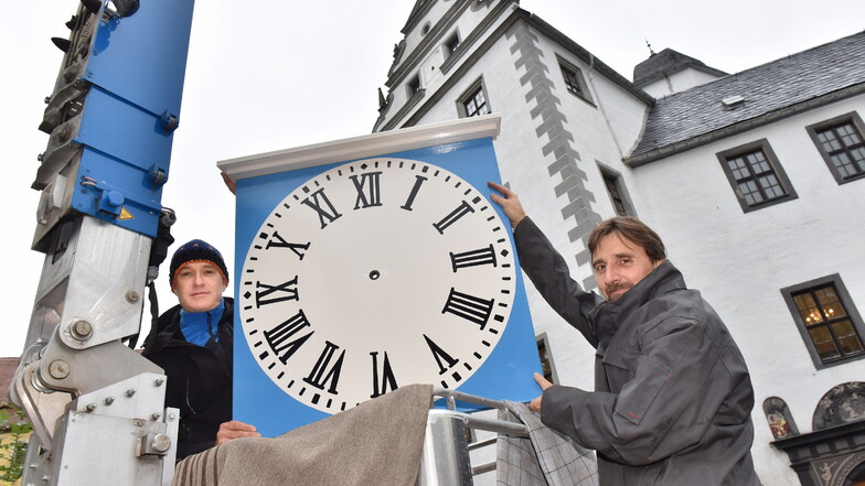 Dachdecker Rico Löwe (li.) und Uhrentechniker Tobias Vogler bringen mit einer Hebebühne das neue Zifferblatt hinauf zur Montage am Lauensteiner Schlossturm.
