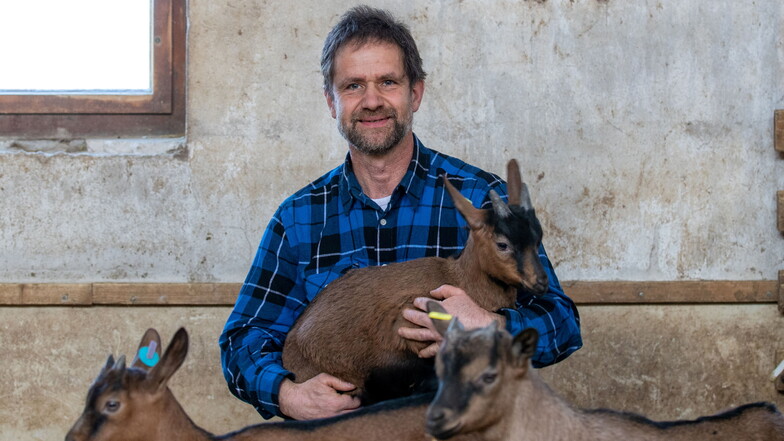 Rolf Seim vom Ziegenhof Seim in Lauterbach im Stall mit einer kleinen Ziege im Arm.