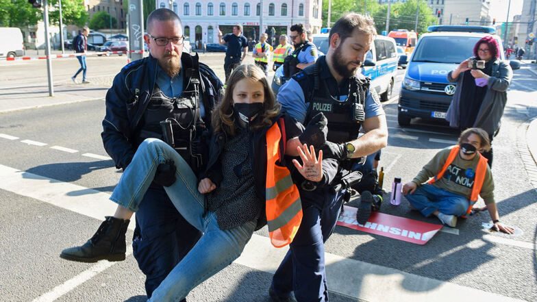 Klima-Aktivistin Lina Schinköthe wird von Polizeibeamten von der Straße getragen.