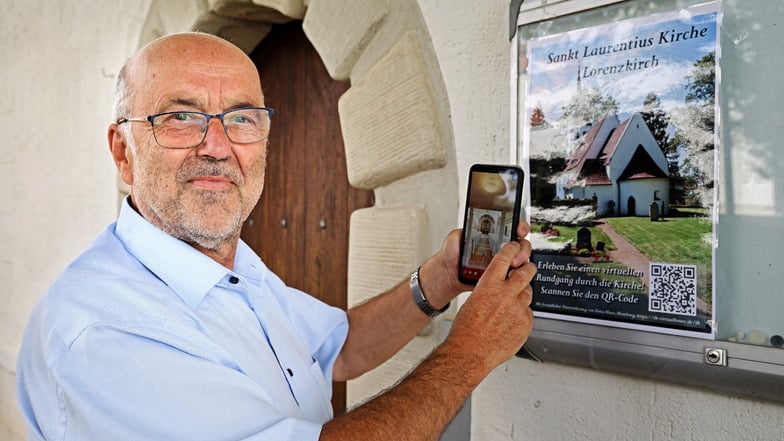Der Zeithainer Kirchenvorstand Michael Ahner hält sein Handy an den QR-Code auf dem Plakat, um den 3D-Rundgang durch die Laurentiuskirche auszuprobieren. Eine Hamburgerin hat die Aufnahmen gemacht und der Kirchgemeinde kostenlos zur Verfügung gestellt.