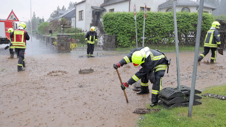 Feuerwehrleute sind im Ortsteil Geyersdorf mit Aufräumarbeiten beschäftigt.