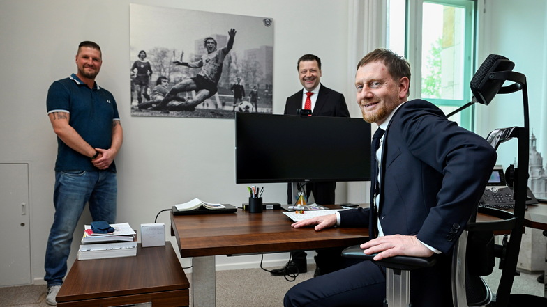 Ein Bild von  Hans-Jürgen „Dixie“ Dörner ziert das Büro des sächsischen Ministerpräsident. Am Freitag erhielt Michael Kretschmer von Sohn Steffen Dörner und Dynamo-Präsident Holger Scholze eine Aufnahme des Dynamo-Rekordspielers.