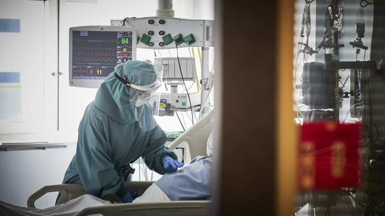 Eine medizinische Mitarbeiterin behandelt in einer Intensivstation einen Patienten. Auch im Landkreis Meißen steigt die Anzahl der Covid-Patienten auf Intensivstationen an. Sechs Patienten sind jetzt gestorben.