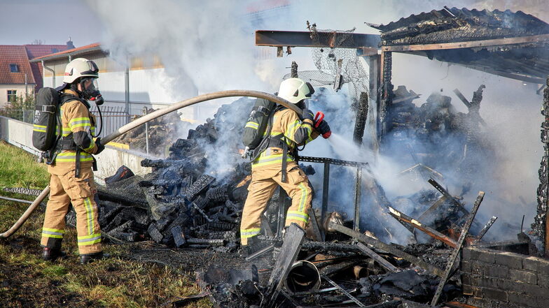 Feuerwehrleute versuchen einen brennenden Schuppen in Borthen zu löschen.