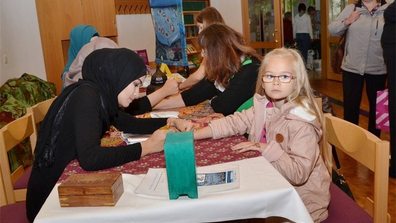 Am Stand des Mehrgenerationshauses des Martinshofes Rothenburg bemalen junge Tschetscheninnen die Hände und Arme der Kinder mit Henna.