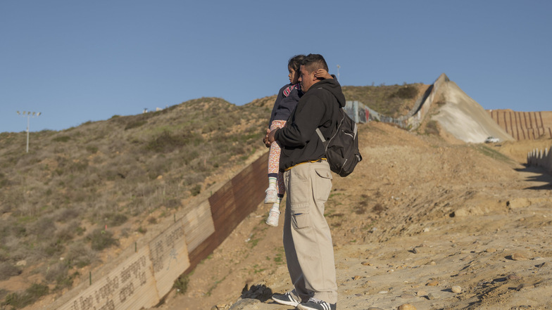 Ein Migrant aus Honduras hält seine Tochter im Arm, während sie in Richtung USA blicken, bevor sie über den Grenzzaun klettern. 