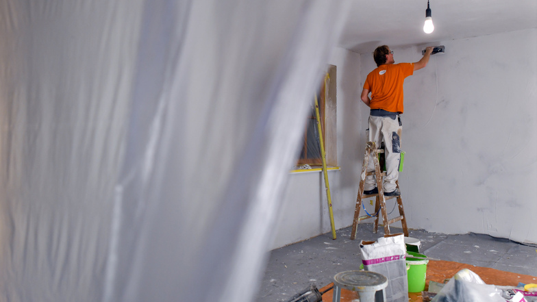 Ein Maler spachtelt die Wände eines Zimmers. Die Auftragsbücher der Handwerker in der Region Döbeln sind trotz Corona-Krise offenbar gut gefüllt.