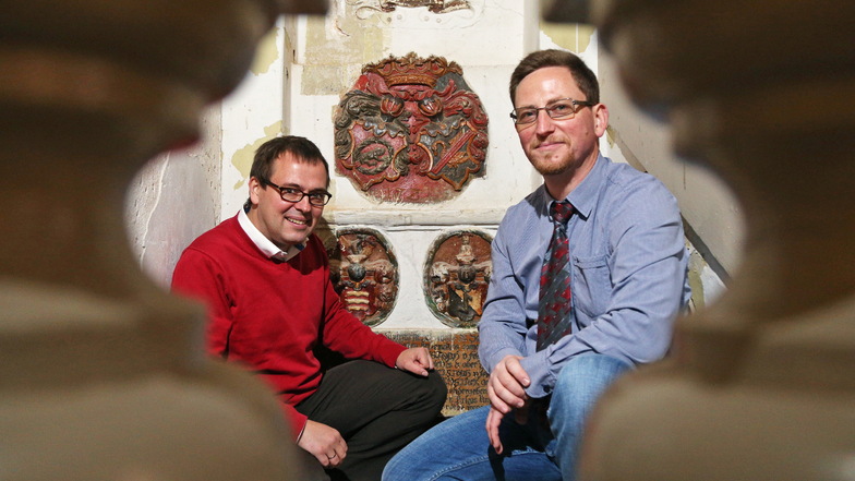 Matthias Donath (links), Vorsitzender des Freundeskreises Schlösserland Sachsen, und der Hirschsteiner Bürgermeister Conrad Seifert (CDU) vor den historischen Wappen.