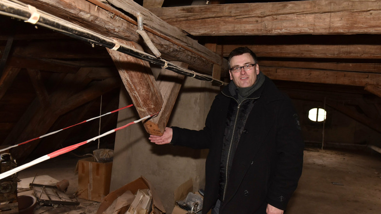 Konstantin Hermann zeigt hier auf dem Dachboden eine Stelle, wo ein Sparren herausgesägt worden ist. Solche Schäden will er wieder reparieren.