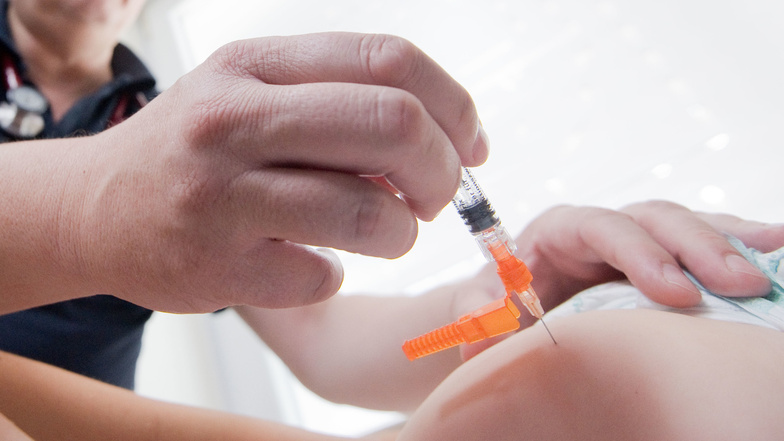 Ein Kinderarzt impft ein einjähriges Kind in den Oberschenkel
