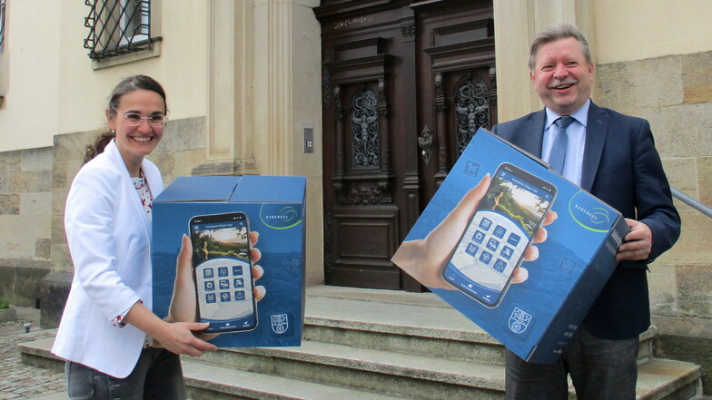 Oberbürgermeister Bert Wendsche (r.) und Daniela Bollmann, Leiterin Zentrale Leitstelle, stellten im Rathaus die Bürger-App vor. Auf Kartons war die neue Funktion für Smartphone und Tablet abgebildet.