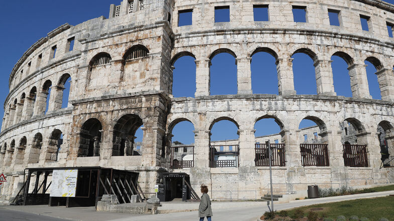 Eine arbeitslose Fremdenführerin geht am römischen Amphitheater in Pula vorbei. Dort drängen sich normalerweise Touristen. Wegen der Corona-Beschränkungen ist das Amphitheater geschlossen.