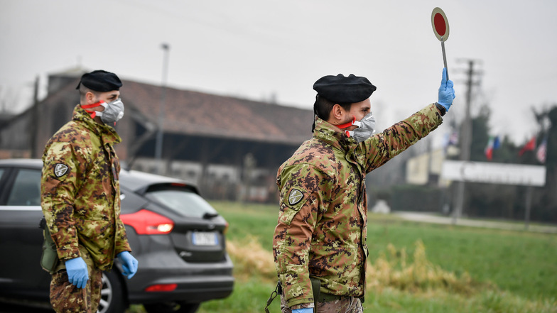 Ein Soldat hält an einer Straßensperre vor der roten Zone von Turano Lodigiano (Italien) eine Winkerkelle in die Höhe. Solche Szenarien sind auch in Deutschland im Fall einer Epidemie möglich.